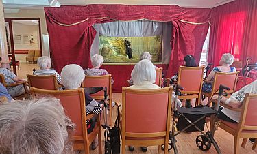 Die Bewohnerinnen und Bewohner genießen den Auftritt des Puppentheaters. 
