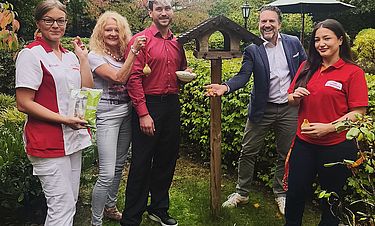 Im Garten der Kursana Villa: Direktor Folkert Moormann-Krause (rechts) und Stellvertreter Hannes Schwarz präsentieren mit ihren Kolleginnen das neue Vogelhaus und herzhafte Angebote für die heimische Tierwelt.