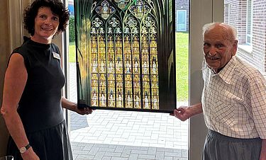 Britta Bierhaus, Leiterin des Kursana Domizils, und Konrad Hoffmeister vor dem Foto des Westfensters im Andachtsraum.