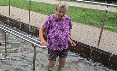 Eine Bewohnerin steht im Kneippbecken und genießt die Abkühlung. 