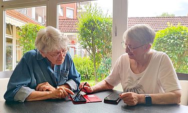Elke Purtzel (r.) unterstützt ihre Mitbewohnerin Kerstin Gerdsen in der Kursana Residenz Wedel bei Fragen zum Smartphone. 