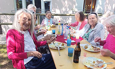 Die Bewohnerinnen und Gäste genießen das reichhaltige Essen beim Sommerfest. 
