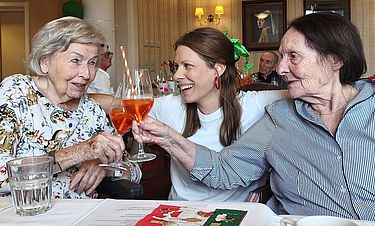 So kann Dolce Vita aussehen: Rosemarie Lang (links) und Rosemarie Dochantschi (rechts) stoßen beim Sommerfest in der Kursana Villa Königstein mit einem Aperol Spritz an und freuen sich mit Sarah Leonardo vom Team der Sozialen Betreuung.